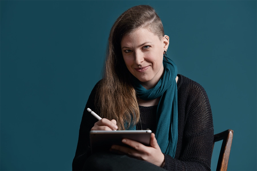 Brand Design mit Freelancer Stefanie von Corliss Design zeichnet am iPad und blickt dabei in die Kamera