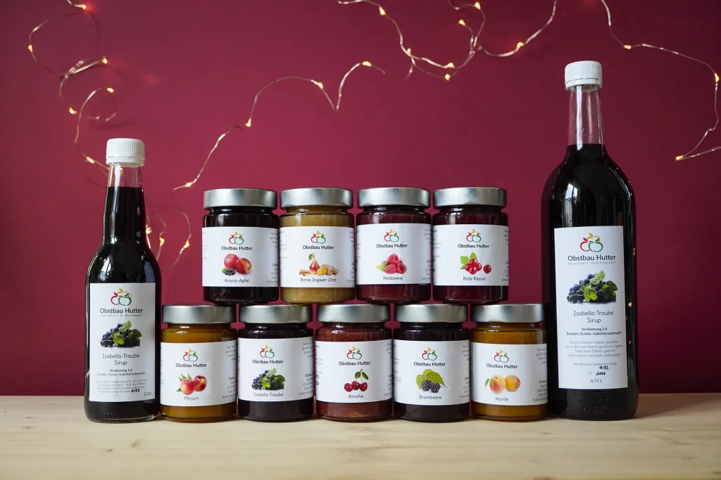 Logo Redesign und Verpackungsdesign von Corliss Design für Obstbau Hutter, zu sehen ist eine Übersicht aller Marmeladesorten im neuen Design sowie zwei Sirup Flaschen