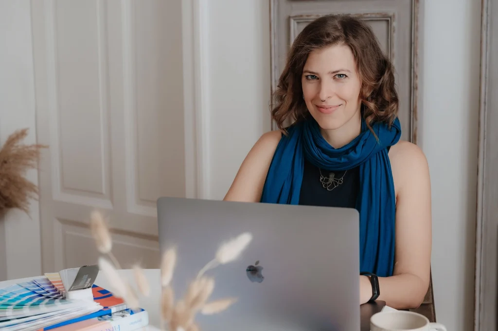 Stefanie Schafzahl von Corliss Design am Tisch mit Laptop und Pantone Fächer